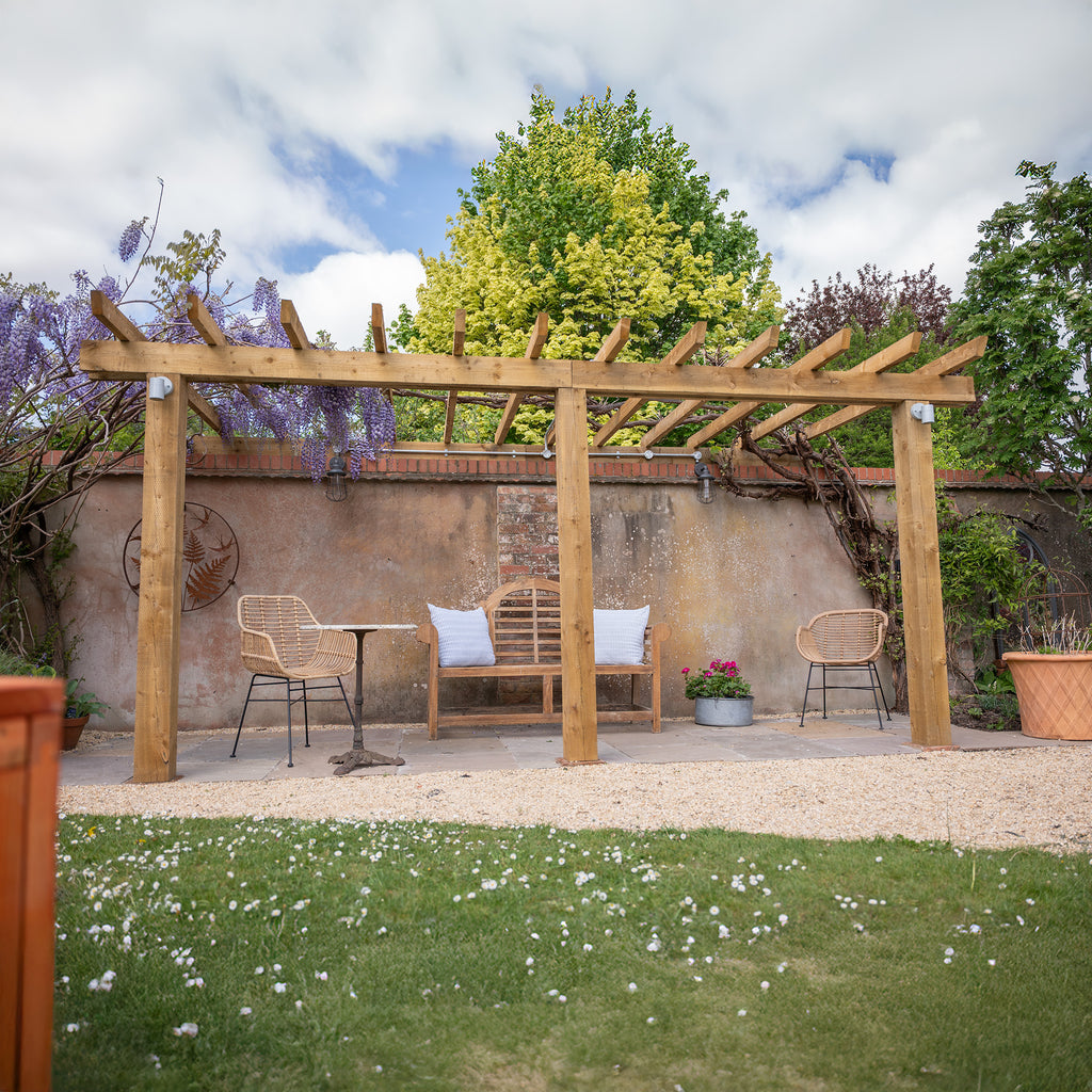 Wooden Pergola with open roof lean-to design attached to house wall, creating sheltered outdoor seating area