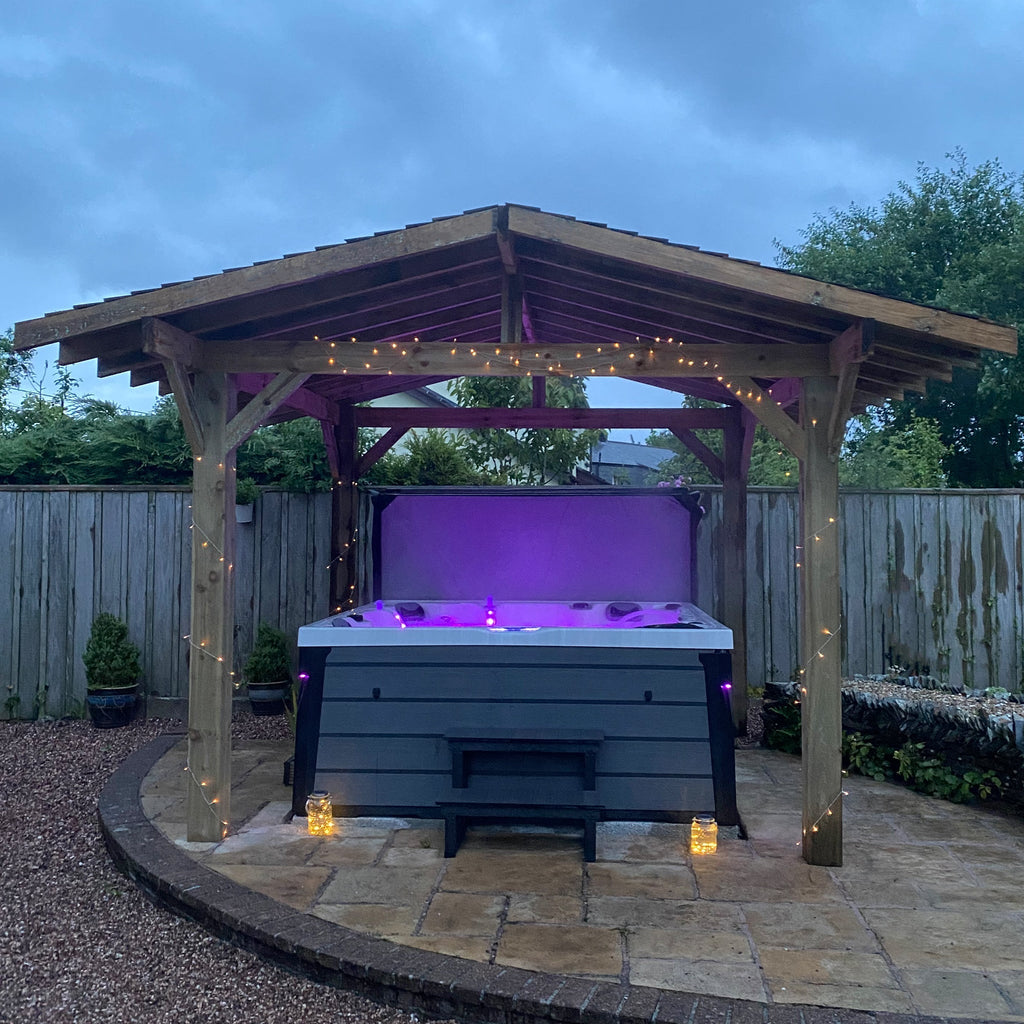 Premium Featheredge Pergola made from wood, shown around a lit up hot tub