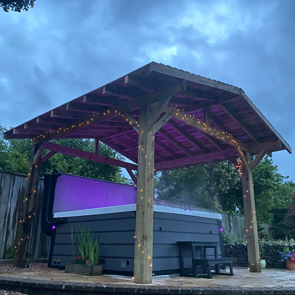 Pressure Treated Pergola With Featheredge Roof shown around a hot tub at night