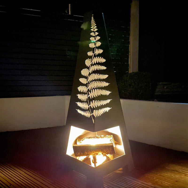 Matte black garden chiminea with fern cut out design on decking